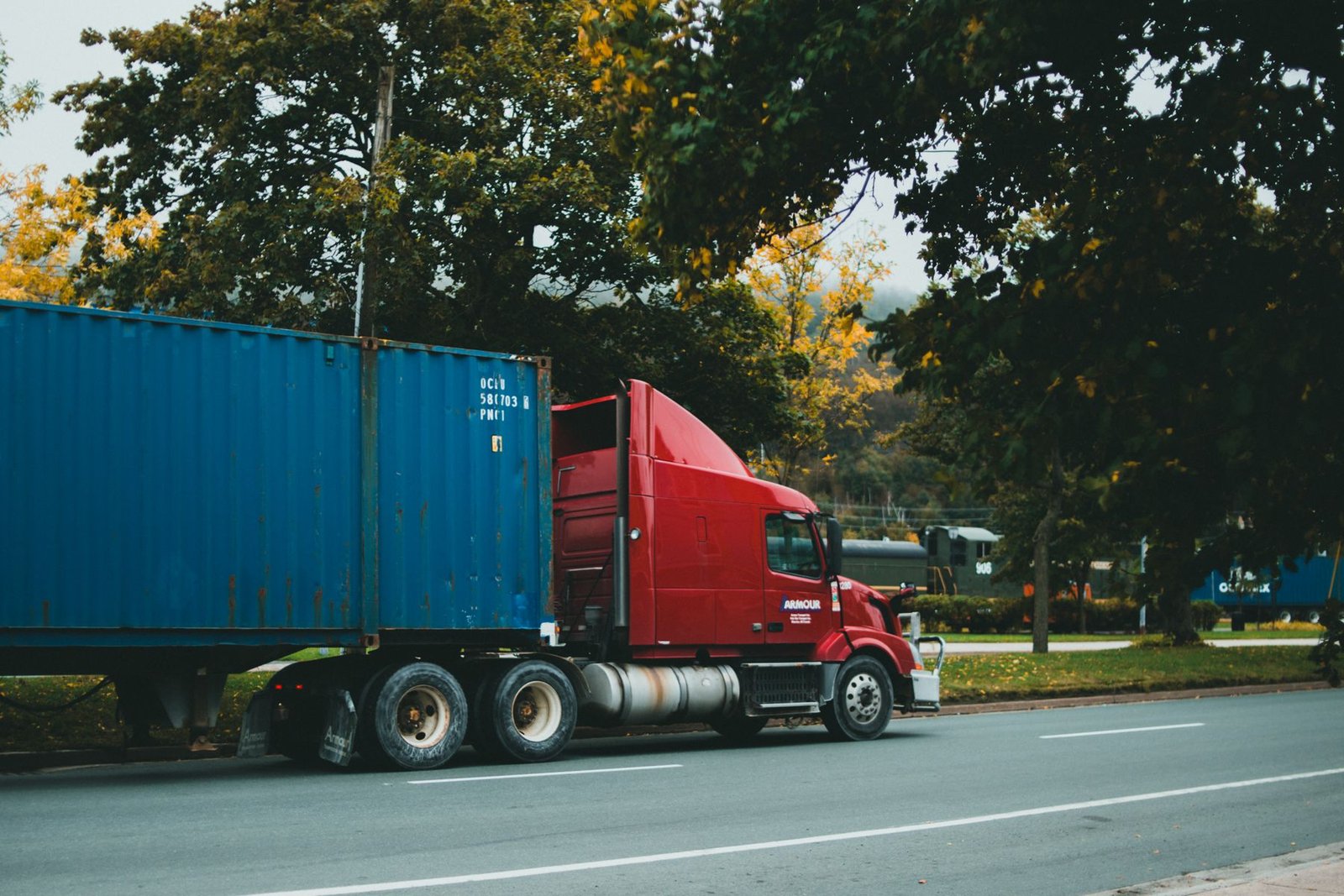 Red semi truck hauling a container on the road